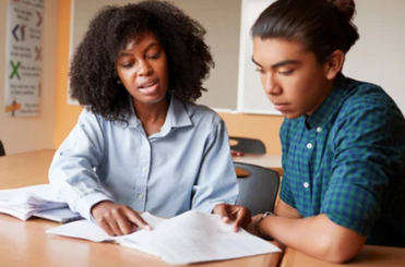 Educator tutoring a student in person at study desk